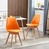 Two orange dining chairs are placed around a white table in a dining room setting. Voir les images du produit