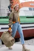 A woman walks with a duffel bag in front of a boat. Voir les images du produit