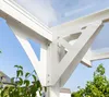 Close-up of a white aluminum carport structure with a transparent roof, showing the support beams and brackets against a blue sky and some greenery. Podgląd zdjęcia produktu