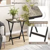 A small folding table with a marble-like top and black metal legs, set up indoors with a plant and a cup of coffee and cake on it. Inset images highlight the table's rounded corners and reinforced crossbar. Produktbild-Vorschau