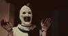 A terrifying clown character from a horror movie is shown holding a scalpel and looking at the camera. Produktbild-Vorschau