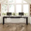 A modern home office setup with a long black desk, two computer monitors, and two white chairs, positioned in front of large windows with a view of trees. Produktbild-Vorschau