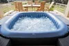An inflatable hot tub filled with bubbling water is shown on a patio, with outdoor furniture and a railing in the background. Náhľad obrázku produktu