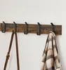 A wooden coat rack with black hooks mounted on a white wall. Produktbild-Vorschau