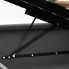 A close-up view of a black metal gas strut mechanism attached to a bed frame. Produktbild-Vorschau