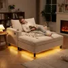 A woman relaxing on a sofa with a cat, in a living room setting with a fireplace and bookshelf. Produktbild-Vorschau