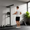 A man is using a wall-mounted lat pulldown machine in a home gym. Produktbild-Vorschau