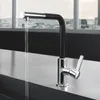 A modern kitchen faucet with water running, set against a city skyline visible through a large window. Produktbild-Vorschau