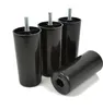 Four black plastic furniture feet with threaded bolts are arranged on a white background. One foot is lying on its side in the foreground, while three are standing upright behind it. Voir les images du produit
