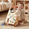 A baby is playing with a wooden walker in a nursery. Produktbild-Vorschau