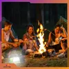 People are sitting around a campfire at night, roasting marshmallows. A camping lantern is visible in the foreground. Podgląd zdjęcia produktu