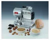 A chrome electric grater with various food items like nuts, chocolate, and bread arranged around it. Podgląd zdjęcia produktu
