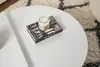 A white coffee table with a book and a candle on it, placed on a rug. Produktbild-Vorschau