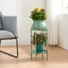 A plant stand with two potted plants next to a chair in a room. Podgląd zdjęcia produktu
