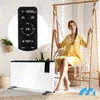 A woman sits in a hanging chair next to a white electric heater, with a remote control visible in a circular overlay. Voir les images du produit
