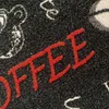 A close-up view of a rug with the word "COFFEE" written in red letters. Anteprima dell’immagine prodotto