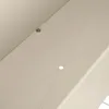 A close-up view of a light-colored surface with two small holes and a metallic fastener. Produktbild-Vorschau