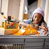 A young girl plays with a LEGO City Stunt Park playset, featuring a motorcycle and a spider cage. Podgląd zdjęcia produktu