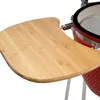 A close-up view of a red ceramic grill with a wooden side shelf. Produktbild-Vorschau