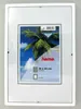 A white picture frame with a tropical scene inside. Produktbild-Vorschau
