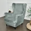 A grey wingback chair cover is shown in a room setting, with a small lamp and books on a side table. Podgląd zdjęcia produktu