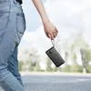 A person holding a black power bank with a strap while walking outdoors. Anteprima dell’immagine prodotto