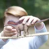 A child's hands holding a toy dinosaur on a rope. Podgląd zdjęcia produktu