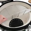 A close-up view of the interior of a ceramic grill, showing a person's hand placing a cooking grate inside. Produktbild-Vorschau