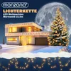 A modern house decorated with Christmas lights, a Christmas tree, and a large moon in the background. Produktbild-Vorschau