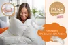 A woman is wrapped in a white duvet, smiling. Produktbild-Vorschau
