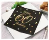 A black napkin with gold polka dots and text "Happy 60 Birthday" is placed on a white plate, set with cutlery. Anteprima dell’immagine prodotto