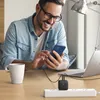 A man is using his phone while it is charging from a wall charger plugged into a power strip on a desk. Anteprima dell’immagine prodotto