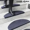 A person wearing black boots walks down a staircase with blue semi-circular stair mats. Anteprima dell’immagine prodotto