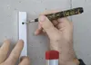 A person is using a marker to make a mark on a metal strip attached to a concrete wall. Produktbild-Vorschau