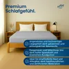 A bed with a gray fitted sheet and white pillows, set in a bedroom with wooden nightstands and a lamp. Produktbild-Vorschau