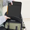 A person is putting a black laptop sleeve into a backpack. Voir les images du produit