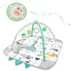 A baby play mat with arches and hanging toys, featuring a dinosaur theme. A small mirror with a baby's reflection is shown in the upper left corner. Anteprima dell’immagine prodotto