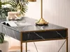 Close-up of a marble desk with gold accents, featuring a lamp and decorative items. Voir les images du produit