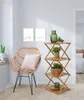 A corner of a room featuring a rattan chair and a wooden folding shelf with plants and a vase. Produktbild-Vorschau