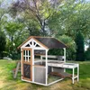 A wooden playhouse with a play kitchen and picnic table set up in a grassy backyard with trees in the background. Anteprima dell’immagine prodotto