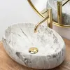 A marble sink with a gold faucet on a wooden surface. Anteprima dell’immagine prodotto