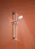 A chrome shower head with water spraying from it, mounted on a shower rail against an orange wall. Produktbild-Vorschau