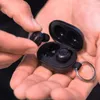 A person is holding a pair of black wireless earbuds and their charging case. Anteprima dell’immagine prodotto