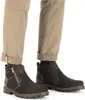 A close-up view of a person wearing black winter boots and tan pants. Anteprima dell’immagine prodotto