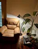 A cozy living room corner with a recliner chair, a floor lamp, and a potted plant. Náhľad obrázku produktu