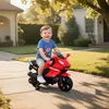 A young child is riding a red toy motorcycle on a paved walkway in front of a house. Produktbild-Vorschau