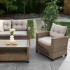 An outdoor lounge set with a sofa, armchair, and coffee table on a patio with a garden in the background. Náhľad obrázku produktu