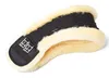 A black horse girth with cream-colored sheepskin lining, shown from a diagonal angle against a white background. Produktbild-Vorschau