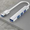A silver USB hub with four blue USB 3.0 ports and a white cable is placed on a gray surface. Produktbild-Vorschau