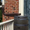 A brown flexible downspout extension is connected to a downspout and empties into a dark barrel, likely a rain barrel, on a wooden deck. A brick wall is visible in the background. Náhled obrázku produktu